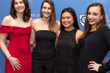 Four female students dressed up and smiling for a photo