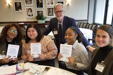 Students at a table holding up a book