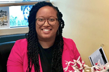 Alum smiling at her desk with flowers