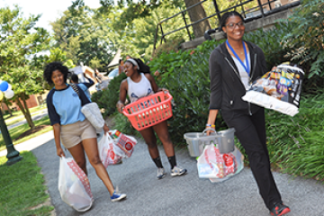 3 students carrying their belongings to move into the residence hall