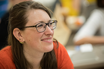 woman with glasses smiling in a classroom