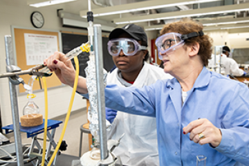 chemistry professor assisting a student in a lab