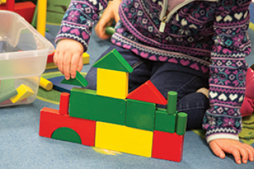 Hands of a child building a block castle