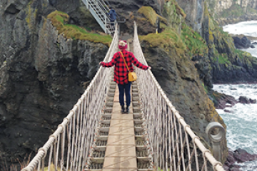 Student on a rope bridge on a mountain next to the water