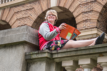 a student holding a book on stone fence