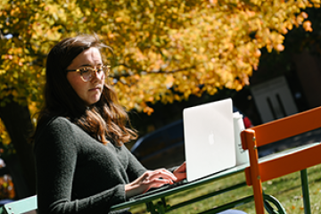 student outside on campus using a laptop