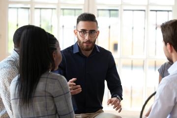 A man is talking to a group of people sitting in a circle