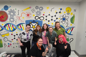 Students standing in front of the STEAM mural