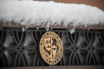 snow on top of a sign with the NDMU seal