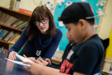 Female teacher talks with a young student in a classroom
