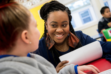 Female teacher smiles at a young student in a classroom