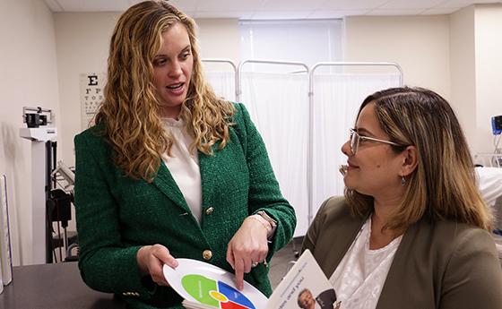 Dr. Ashley Moody and NDMU student Neysa Rios look over pharmacy material in a classroom.