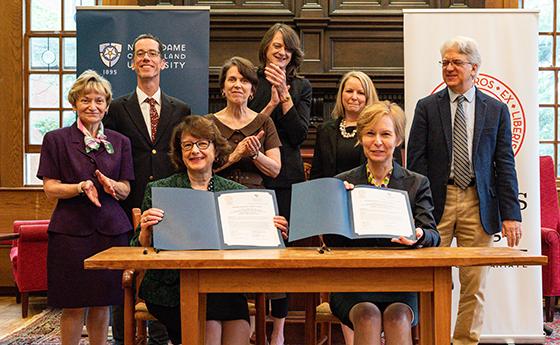 The presidents from NDMU and St. John's hold up their signed agreement certificates.