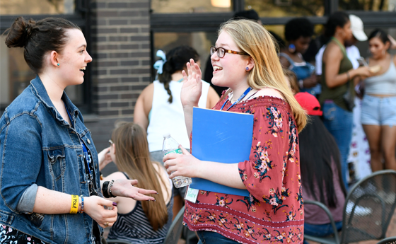Two girls talking with students in the background