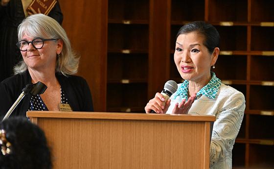 Yumi Hogan (R) delivers remarks, while Dr. Julia Andersen (L), the graduate coordinator for the art therapy program, stands beside her.