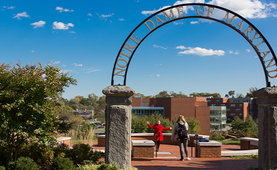 Student getting her picture taken under the NDMU arch