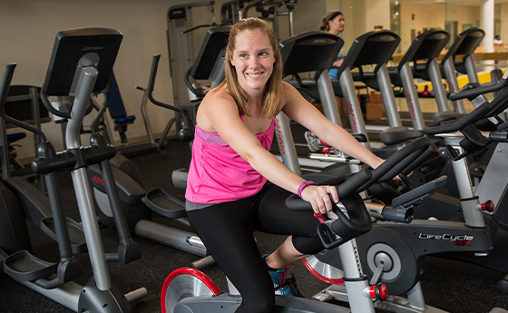 woman smiling on a stationary bike in the gym