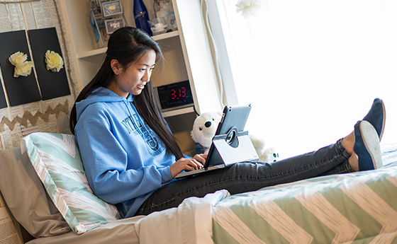 Girl in a dorm looking at her laptop