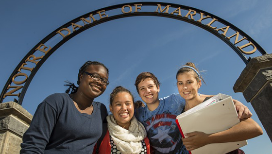 Four Women's College students under the NDMU arch