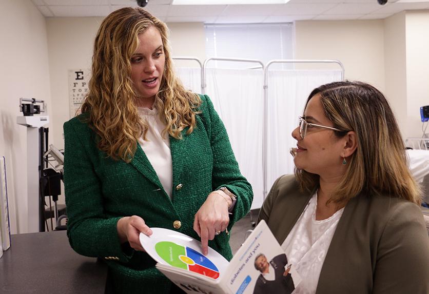 Dr. Ashley Moody and NDMU student Neysa Rios look over pharmacy material in a classroom.