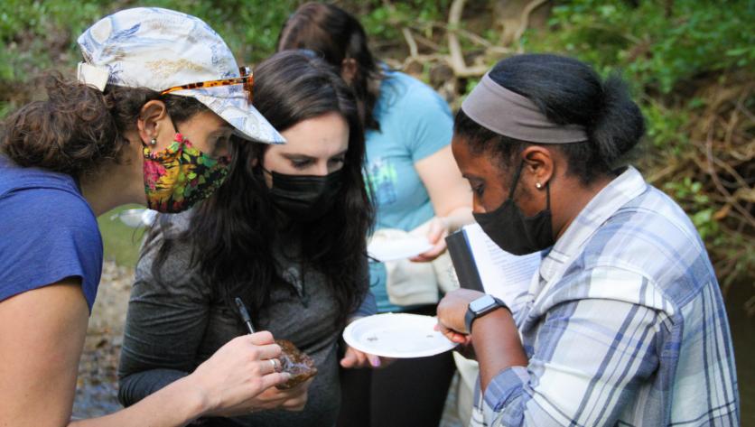 two student and professor view specimen on plate pulled from creek bed