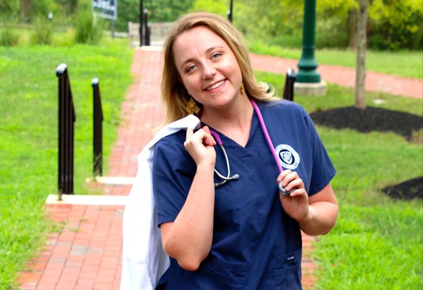 A posed photo of Jennifer Dickensheets outside in her nursing scrubs
