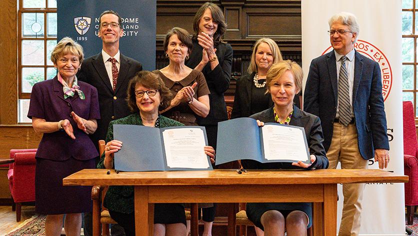 The presidents from NDMU and St. John's hold up their signed agreement certificates.