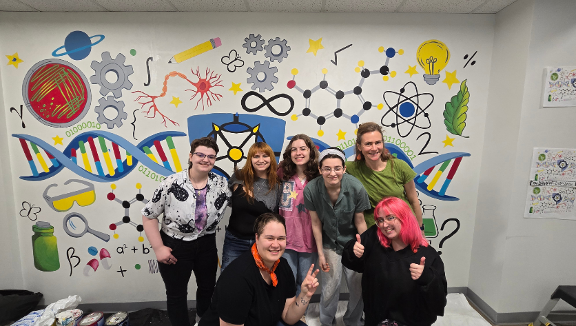 Students standing in front of the STEAM mural
