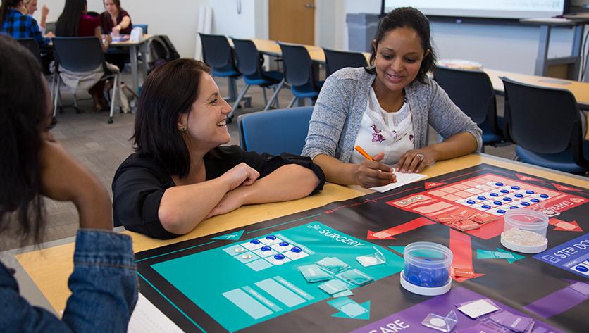 teach kneels down to talk to sitting student at desk