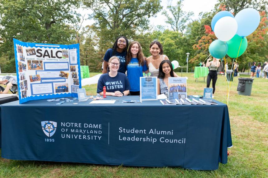 group of students outside at gator fest in front of table