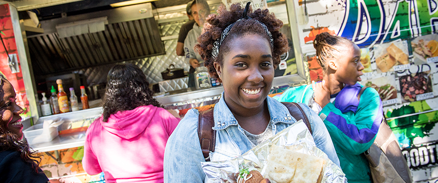 Student with food in front of a food truck