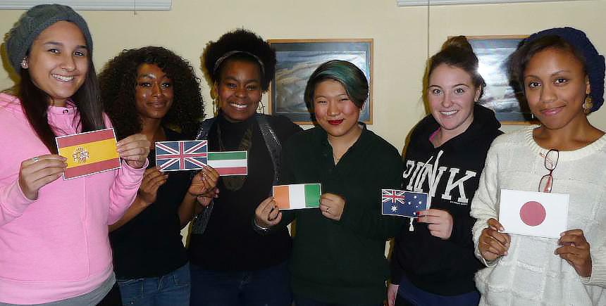 Six smiling students holding flags from different countries