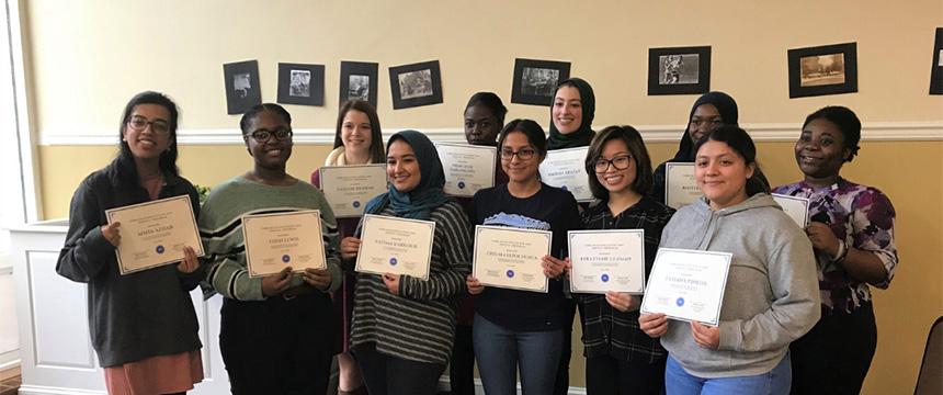 a group of tutors in front of a wall holding certificates