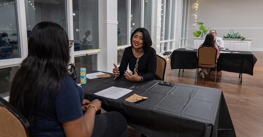 Female student smiling while sitting at a table across from another person