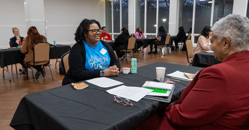 Female student smiling while sitting at a table across from another person
