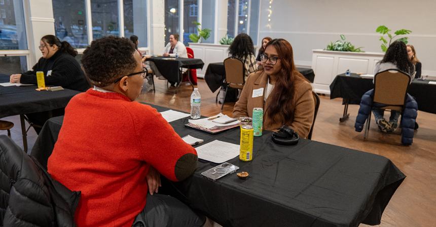 Female student smiling while sitting at a table across from another person