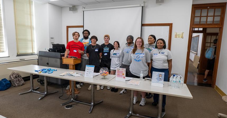 A group of students wearing NDMU gear stand in a line and smile