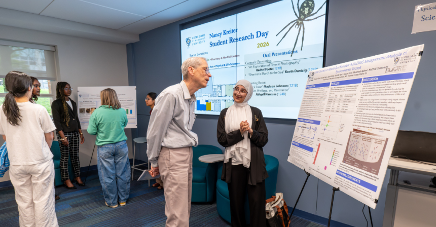 Female student presents poster to a male faculty member