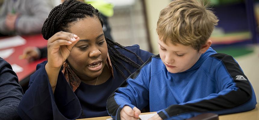 Female teacher looking at a textbook with a child