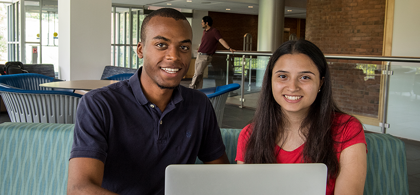 Male and Female student sitting in the library with a laptop