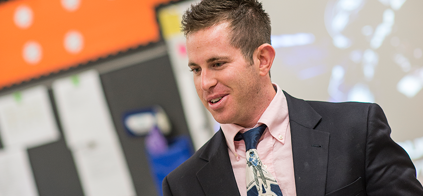 Male teacher in a classroom wearing a suit and tie