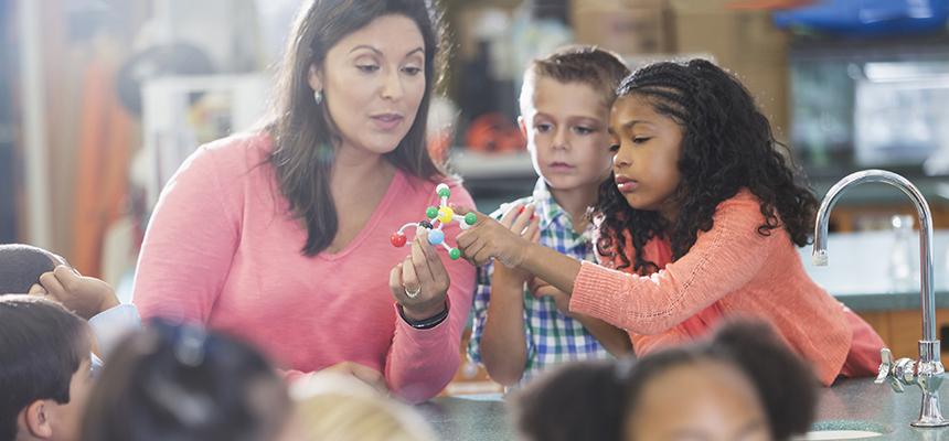 teacher holding up an atom diagram for students to see