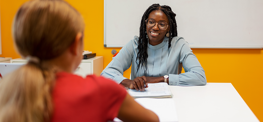 Teacher smiling and having a conversation with a student