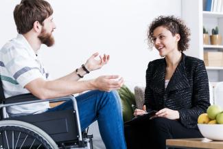 Man in a wheel chair talking to a therapist